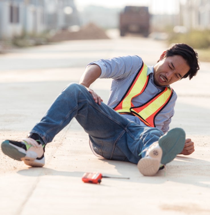 Un travailleur est au sol endolori. Il semble avoir fait une chute.