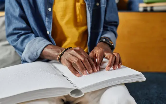 personne aveugle qui lit un livre en braille