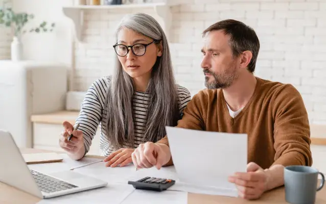 Famille de couple d’âge moyen mature femme et mari comptant les fonds, les déclarations d’épargne, les investissements, la paperasse, les documents financiers, la faillite, le procès, les factures, la pension avec ordinateur portable.