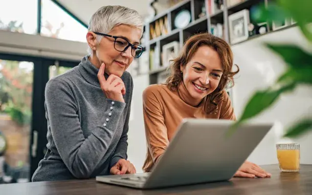 Deux femmes, mère et fille, regardant l’ordinateur portatif à l’intérieur.
