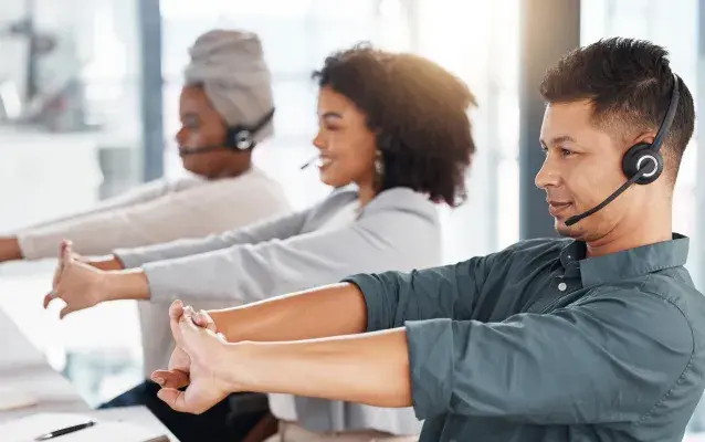 Groupe d’agents de télémarketing de centre d’appels tendant les bras tout en travaillant ensemble dans un bureau. Un consultant hispanique prend une pause pour se préparer à faire fonctionner le service d’assistance pour le service à la clientèle