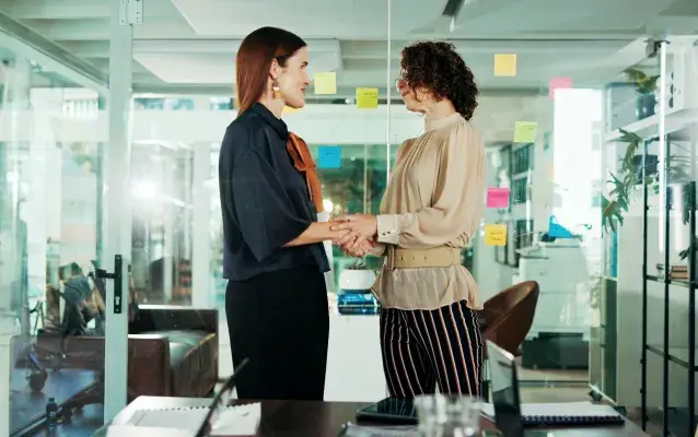 Des femmes qui se serrent la main avec le sourire pour un stage sur le lieu de travail