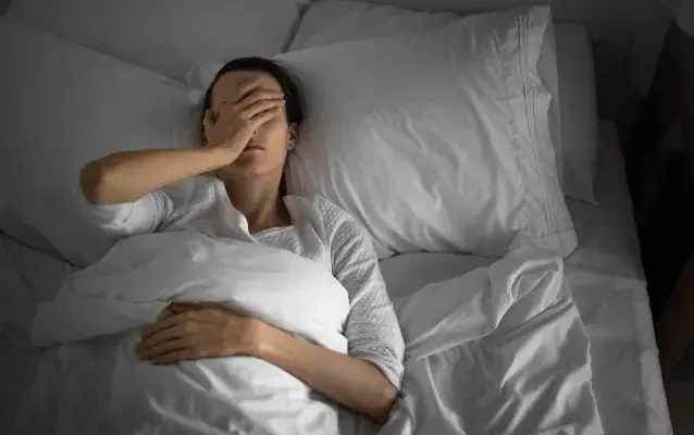 Femme allongée dans son lit qui n'arrive pas à dormir