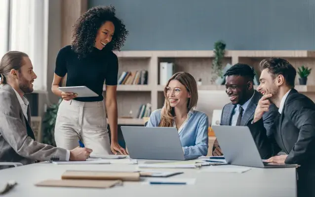 employés hommes et femmes discutant autour d'une femme assise devant son ordinateur