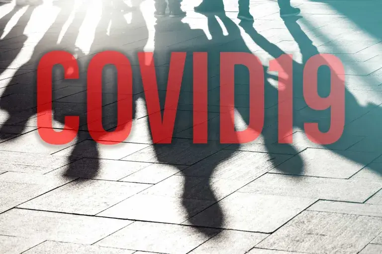 COVID-19 écrit en rouge au sol avec ombre de gens