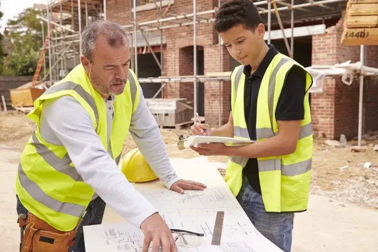 Constructeur sur chantier de construction discuter de travail avec apprenti