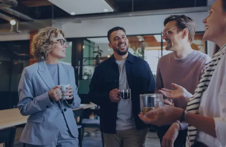 Plusieurs personnes souriantes discutent de façon informelle au travail