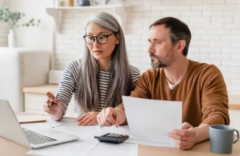 Famille de couple d’âge moyen mature femme et mari comptant les fonds, les déclarations d’épargne, les investissements, la paperasse, les documents financiers, la faillite, le procès, les factures, la pension avec ordinateur portable.
