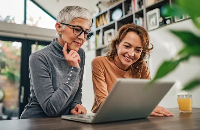 Deux femmes, mère et fille, regardant l’ordinateur portatif à l’intérieur.