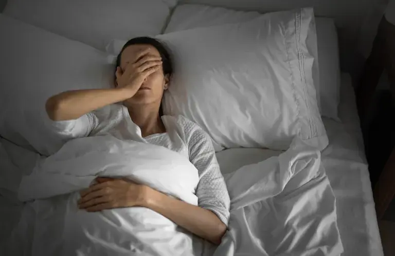Femme allongée dans son lit qui n'arrive pas à dormir