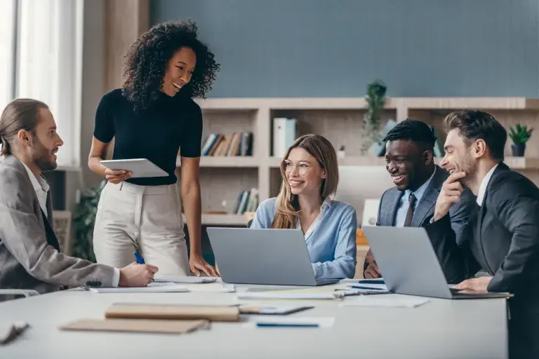 employés hommes et femmes discutant autour d'une femme assise devant son ordinateur