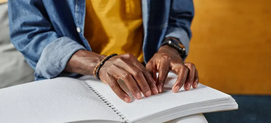 personne aveugle qui lit un livre en braille