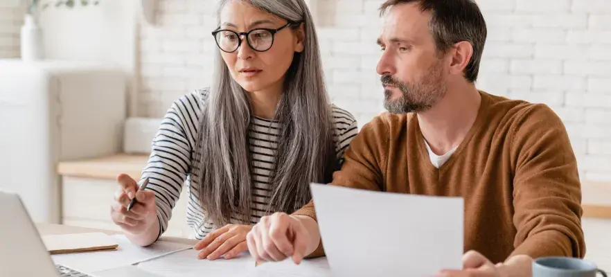 Famille de couple d’âge moyen mature femme et mari comptant les fonds, les déclarations d’épargne, les investissements, la paperasse, les documents financiers, la faillite, le procès, les factures, la pension avec ordinateur portable.