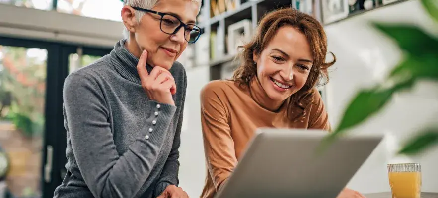 Deux femmes, mère et fille, regardant l’ordinateur portatif à l’intérieur.