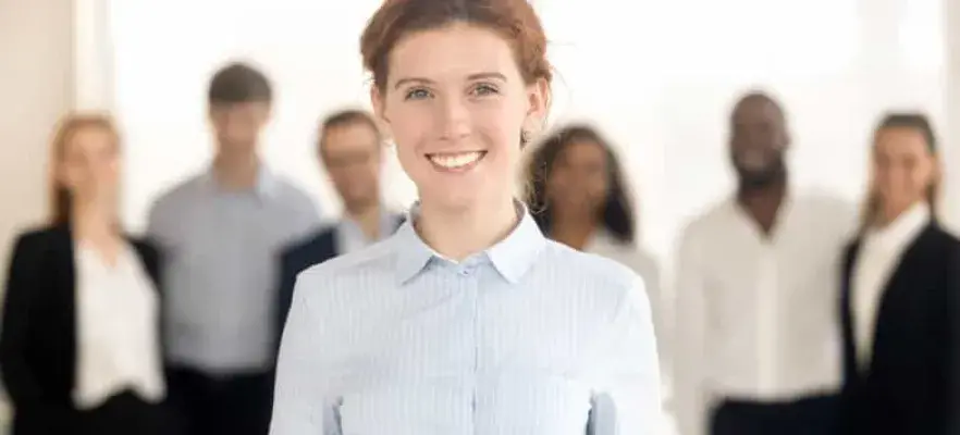 Jeune femme leader heureux regardant dans la caméra posant avec l'équipe